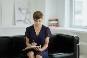 Businesswoman taking notes while sitting on a comfortable sofa in an office setting.